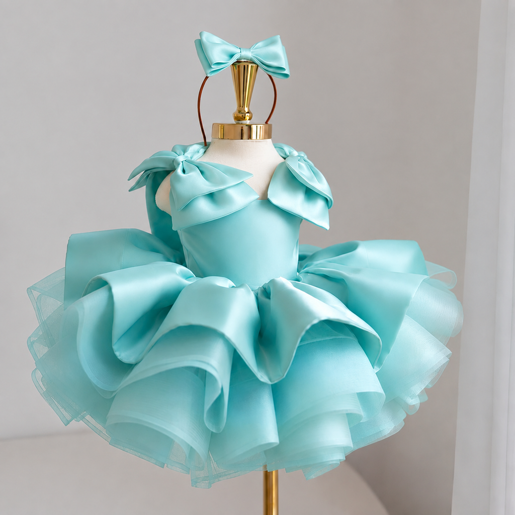 Aqua satin princess dress for girls with sculpted shoulder bows, dramatic layered ruffle skirt and matching aqua bow headband, front view