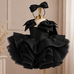 Black satin princess dress for girls with sculpted shoulder bows, dramatic layered ruffle skirt and matching black bow headband, front view