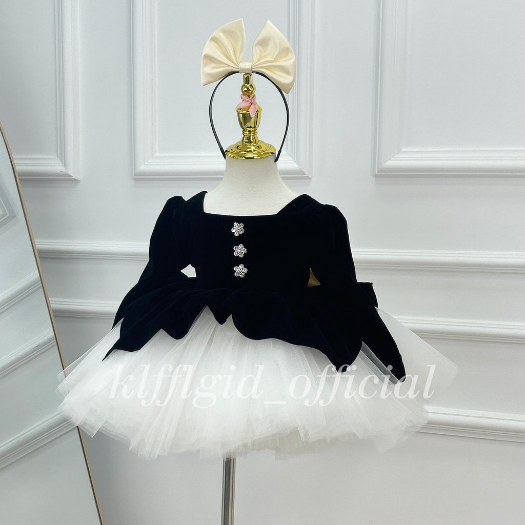 Front view of a black velvet princess dress with a scalloped bodice hem and a voluminous white tutu skirt.
