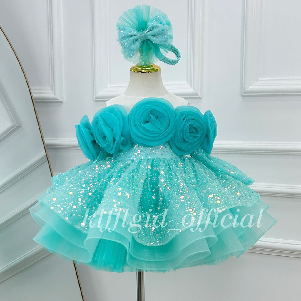 Close-up view of a blue princess dress with sculpted fabric roses, sparkling skirt details, and a full layered silhouette