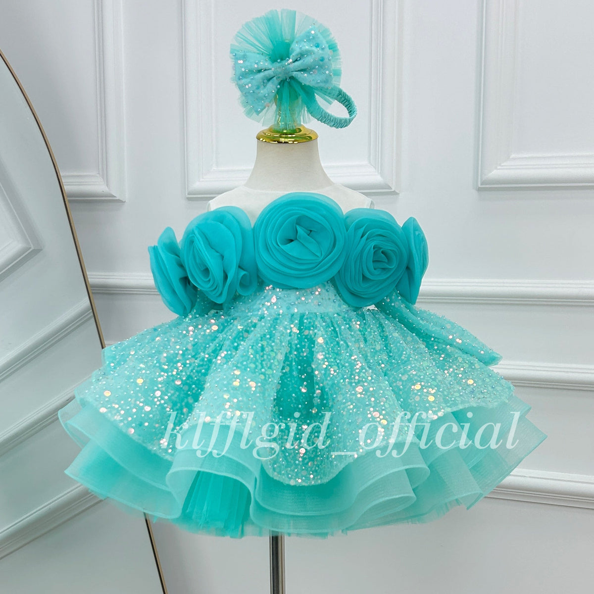 Close-up view of a blue princess dress with sculpted fabric roses, sparkling skirt details, and a full layered silhouette