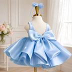 Back view of a light blue satin princess dress for girls with an oversized bow and a voluminous skirt.