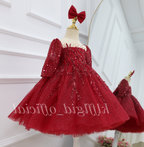 Angled view of a burgundy princess dress for girls with shimmering sequin details, long sleeves, a fitted bodice, and a full flared skirt.