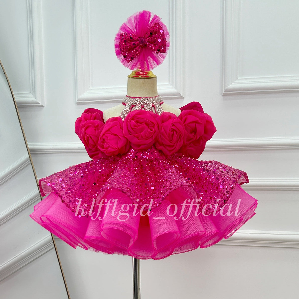 Front view of a hot pink girls' princess dress with dimensional floral decorations, puff sleeves, a full skirt, and a dramatic sheer train.