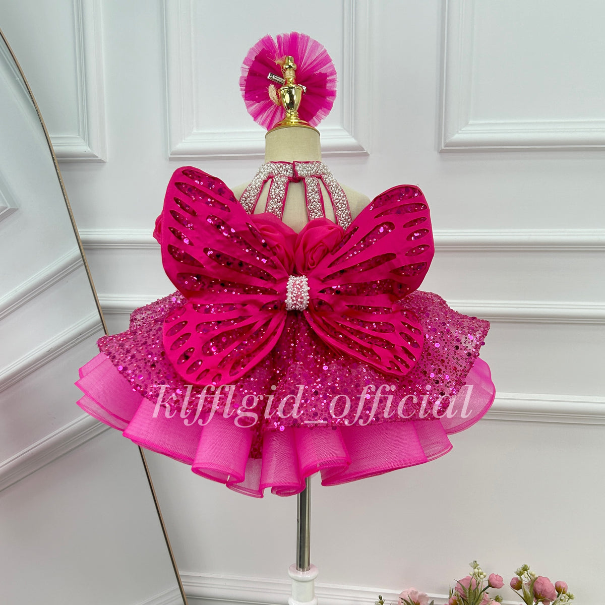 Back view of a hot pink floral princess dress with large flower embellishments and an extended sheer tulle train.