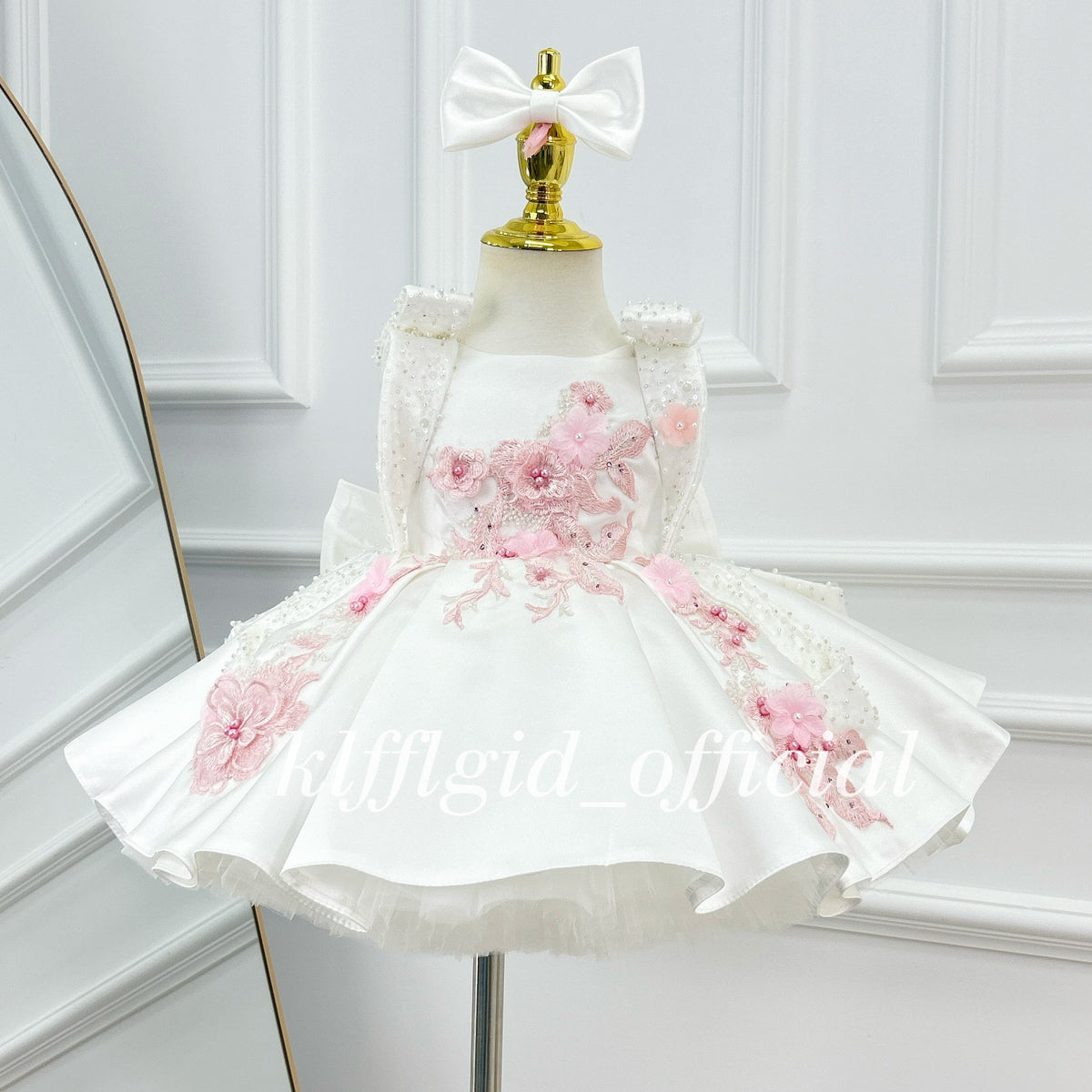 Front view of an ivory girls' party dress with pink floral embroidery, dimensional flower embellishments, decorative shoulder straps, and a voluminous skirt.