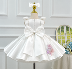 Back view of an ivory girls' princess dress featuring a large satin bow, decorative shoulder straps, a back zipper, and a full flared skirt with floral detailing.