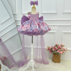 Front view of a lavender girls' princess gown featuring a sparkling bodice, pink and blue floral skirt decorations, an oversized purple bow, and a long sheer tulle train.