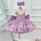Close-up of a lavender girls' princess dress showing a sparkling embellished bodice, pink and blue floral skirt details, pearl-like neckline trim, and decorative pink flower accents.