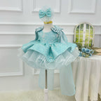 Three-quarter view of a light blue sequin tulle gown for girls with a sparkling bodice, flared layered skirt, shoulder ruffles, and long trailing fabric details.