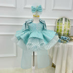 Front view of a light blue girls' sequin tulle princess dress with a sparkling bodice, layered flared skirt, shoulder ruffles, and matching bow headpiece.