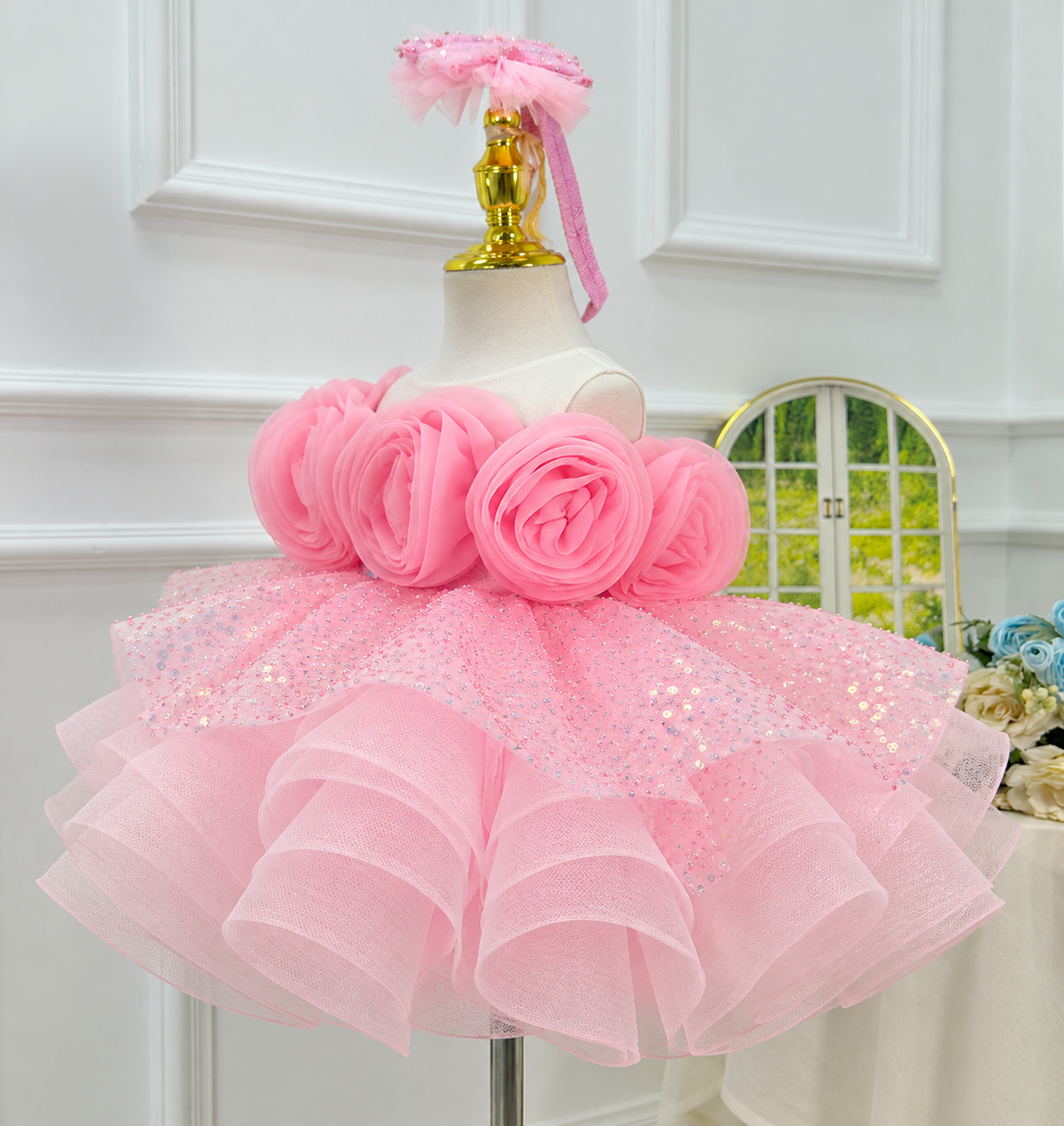 Angled view of a pink princess party dress with three-dimensional rose details, glittering fabric, and a structured full skirt