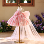 Angled view of pink girls flower girl dress with sparkling petal-shaped skirt layers, floral waist detail and oversized back bow.