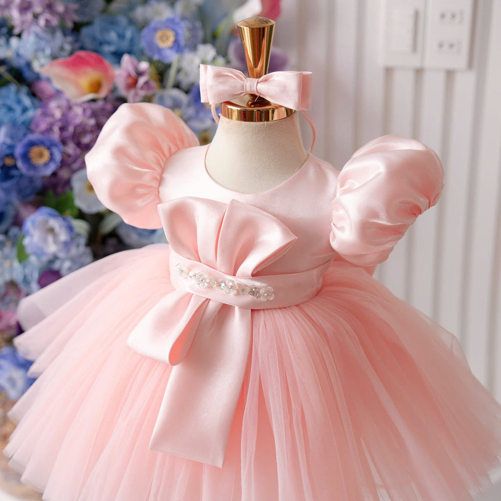 Pink satin princess dress for girls with puff sleeves, sculpted bow bodice detail, jeweled waist belt and voluminous tulle skirt