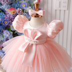 Pink satin princess dress for girls with puff sleeves, sculpted bow bodice detail, jeweled waist belt and voluminous tulle skirt