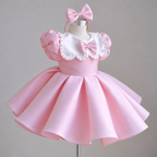 Three-quarter view of a pink satin princess party gown for girls featuring a scalloped white collar, pearl and crystal-style embellishments, puff sleeves, and a matching bow headband.