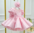 Angled view of a pink satin princess dress with voluminous puff sleeves, a sheer embellished neckline, a wide waistband, and a glossy flared skirt