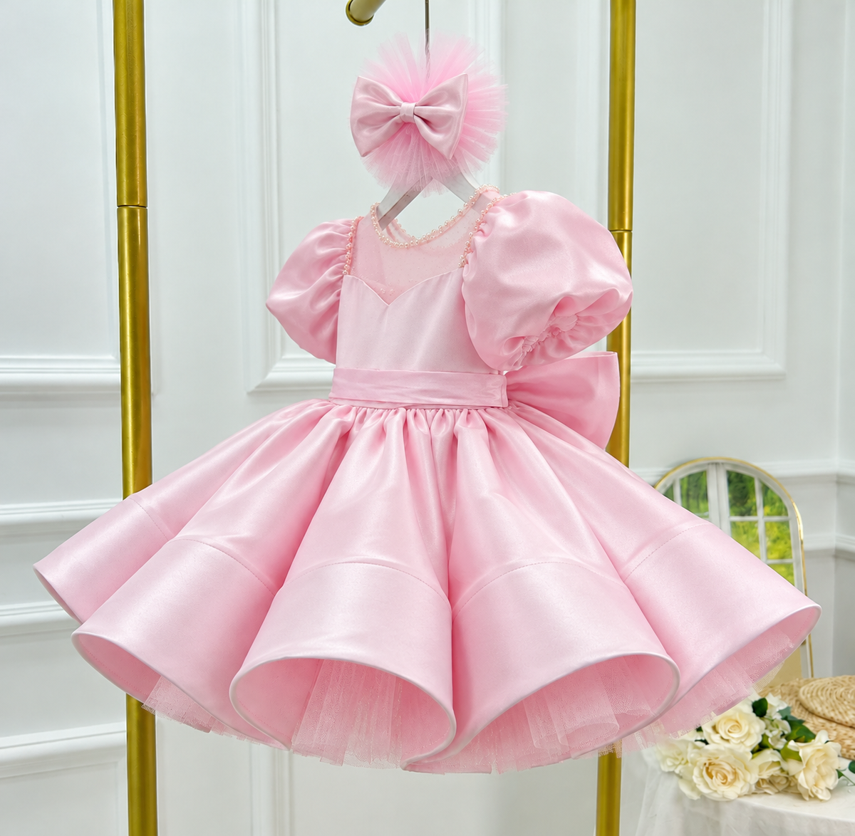 Three-quarter view of a pink girls' party dress with gathered puff sleeves, sparkling neckline trim, a fitted satin bodice, and a structured full skirt