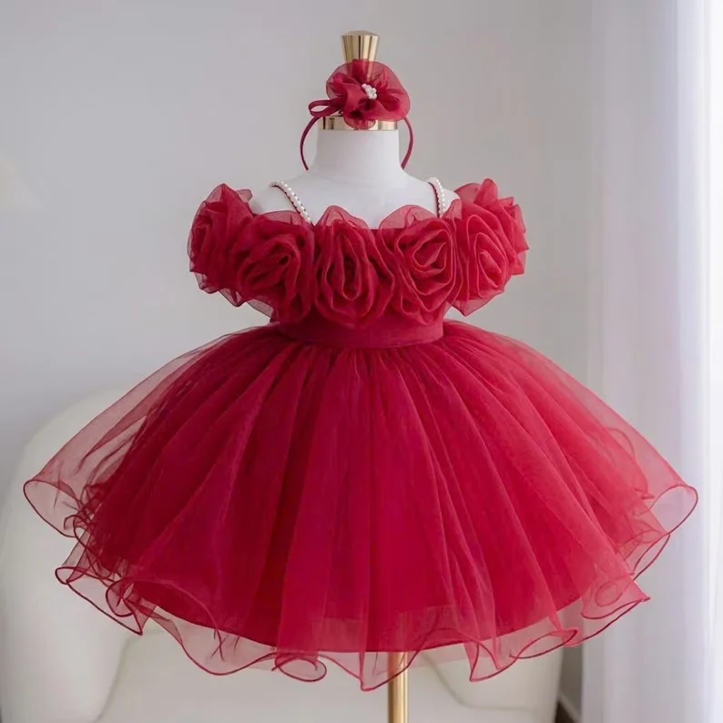 Red girls' birthday party dress with oversized floral bodice decorations, a matching headpiece, and a voluminous layered tulle skirt.
