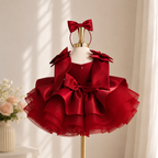 Back view of red satin princess dress for girls with layered shoulder details, rear waist bow and voluminous tiered skirt