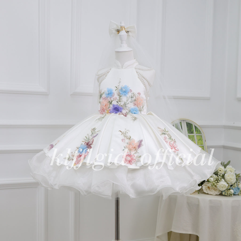 Angled view of a white girls floral princess dress with pearl shoulder details and a layered skirt
