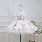 Angled view of a white girls floral princess dress with pearl shoulder details and a layered skirt