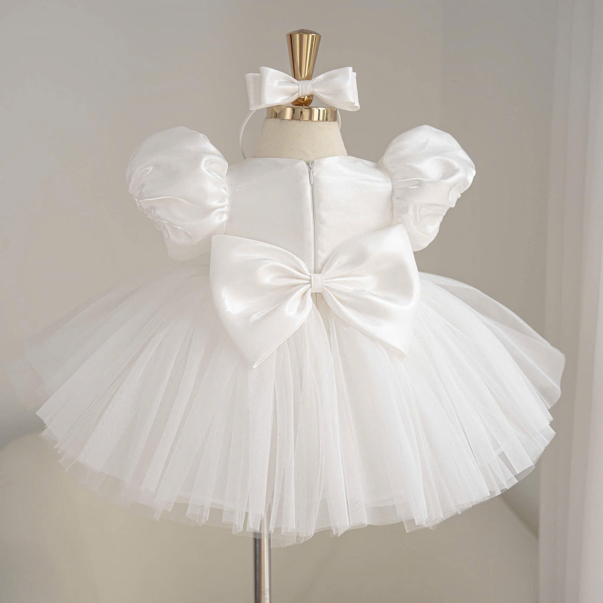 Back view of white girls princess dress with a large satin back bow, puff sleeves and a full layered tulle skirt