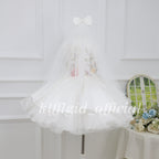 Back view of a white girls princess dress with a long sheer tulle veil and white bow