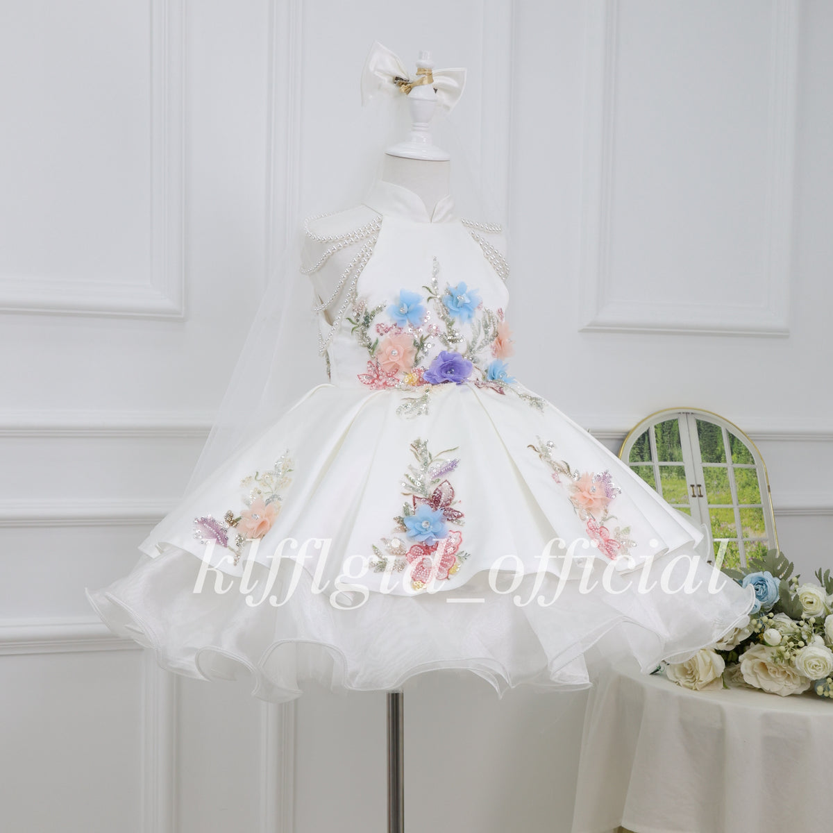 Close view of colorful floral embroidery and pearl-like embellishments on a white girls princess dress