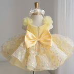 Back view of yellow girls princess dress featuring a large satin bow, textured bodice and layered floral tulle skirt