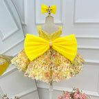 Back view of a yellow girls' princess dress with an oversized satin-look yellow bow, a sparkling bodice, and a full skirt decorated with multicolored floral details.